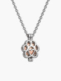 Close-up of a silver paw-shaped locket holding a rose gold pet urn necklace capsule for dog ashes