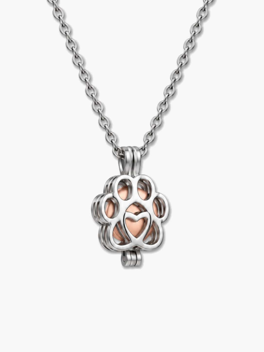 Close-up of a silver paw-shaped locket holding a rose gold pet urn necklace capsule for dog ashes