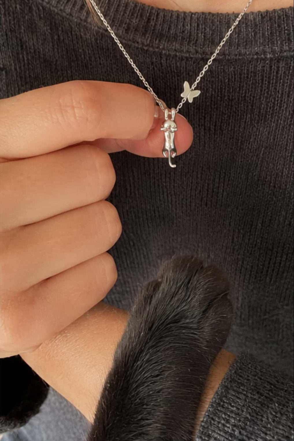 Close-up of S925 sterling silver climbing cat pendant necklace with delicate butterfly charm and cat paw