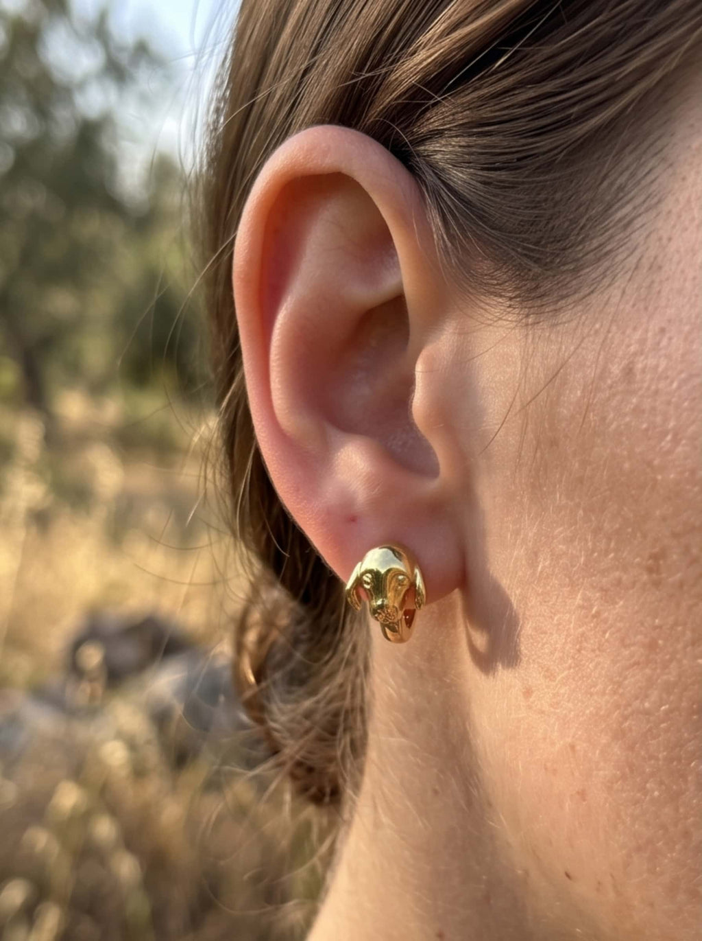 Side portrait of a model showcasing the sculptural detail of the 18K gold plated dog earrings