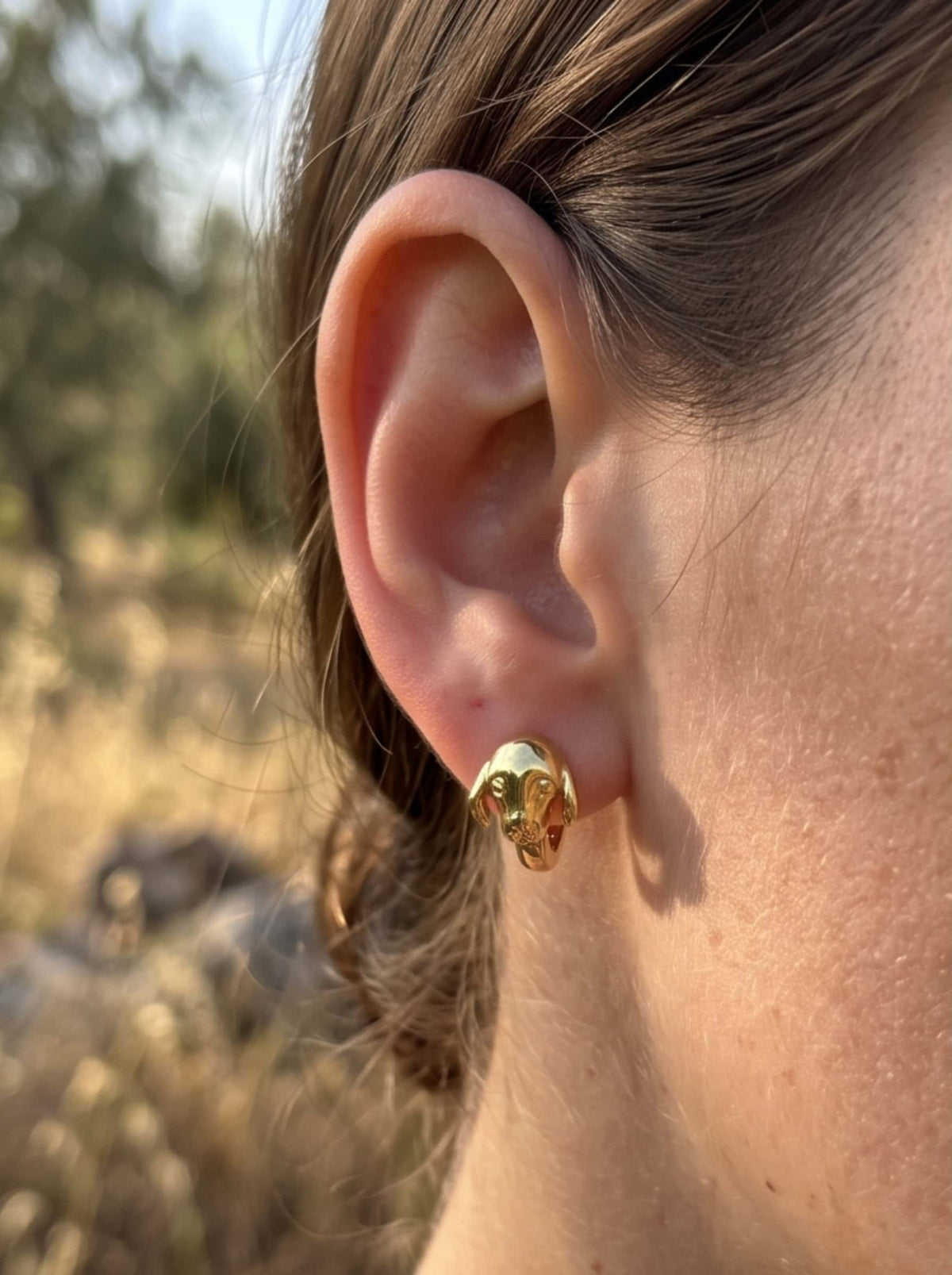 Side portrait of a model showcasing the sculptural detail of the 18K gold plated dog earrings