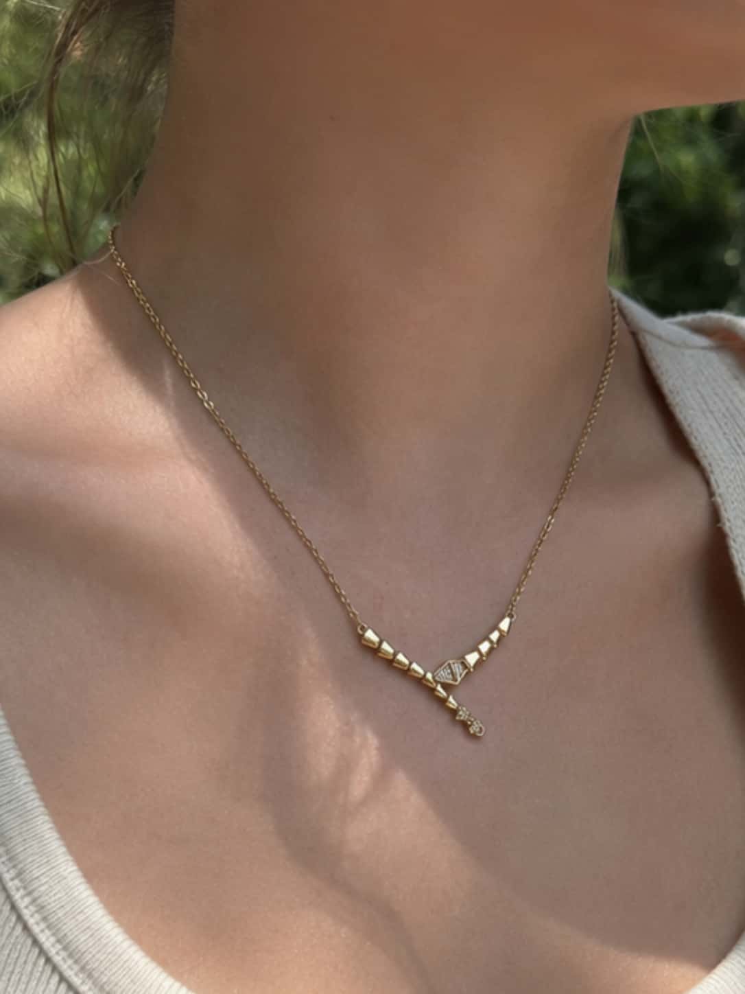 Macro detailed shot of the cubic zirconia pave setting on the head and tail of the serpent necklace worn by a model