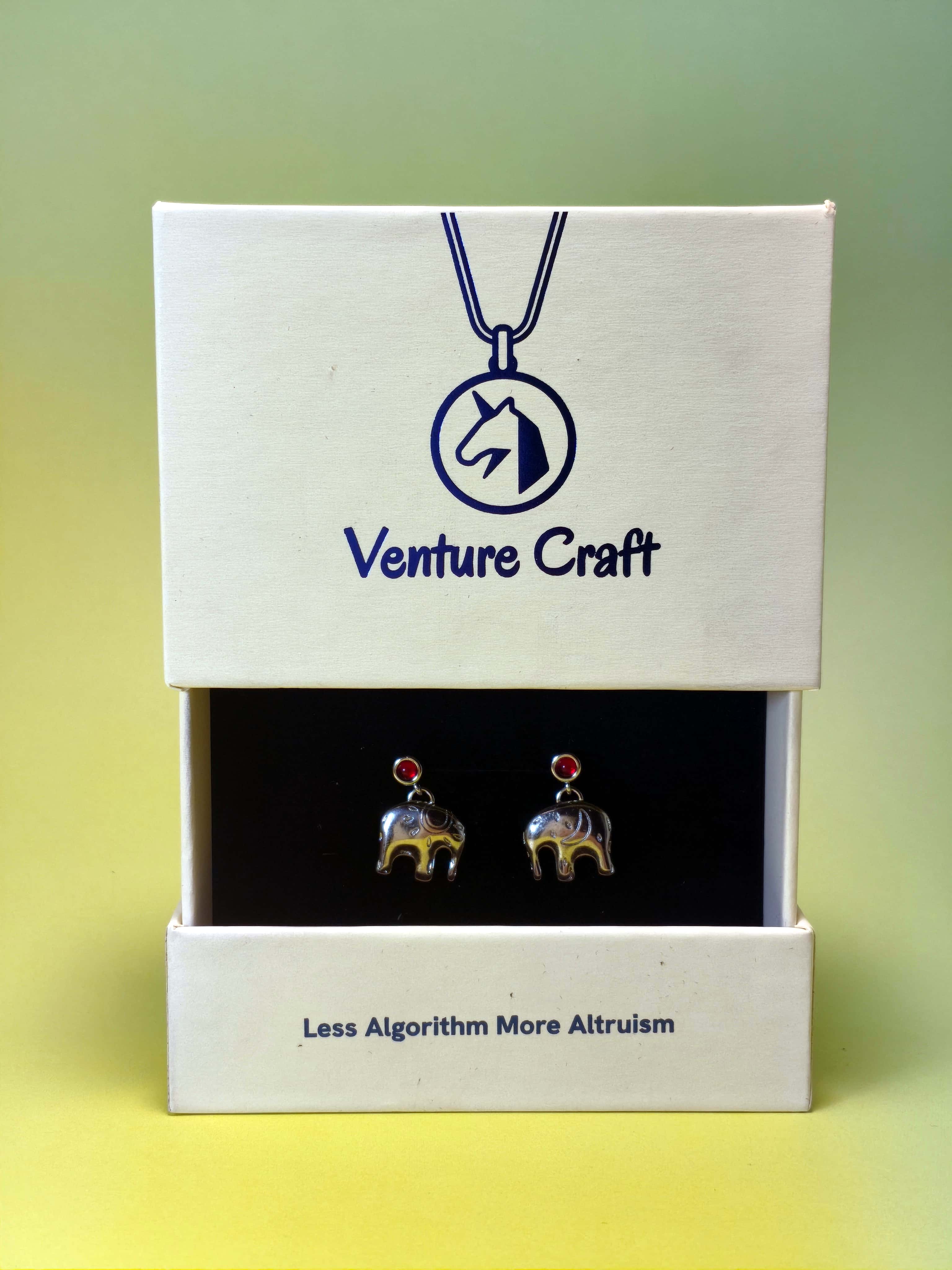 Silver elephant-shaped earrings set in a Venture Craft gift box with a gradient background