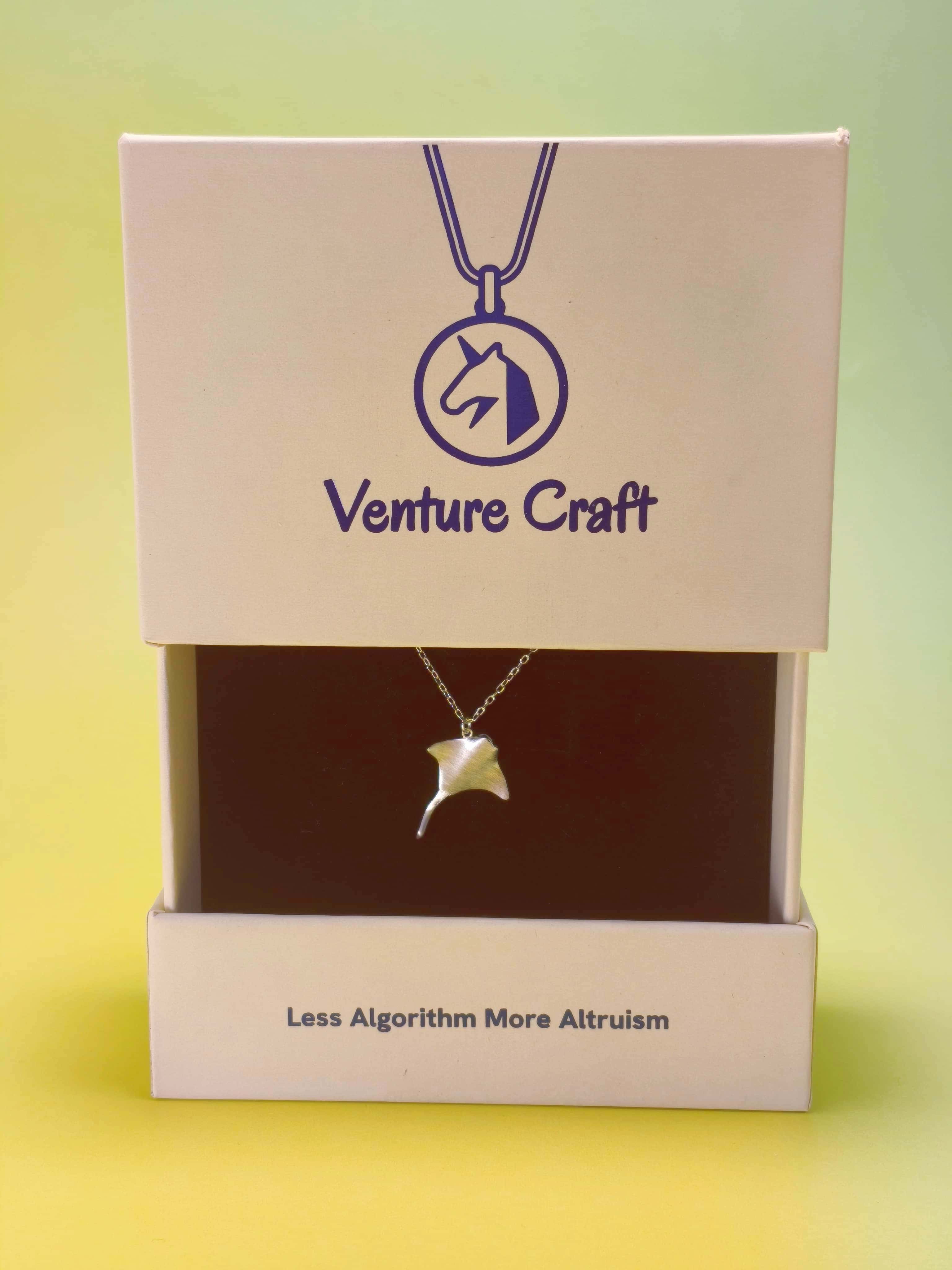 Silver manta ray pendant necklace in a 'Venture Craft' gift box with a gradient background