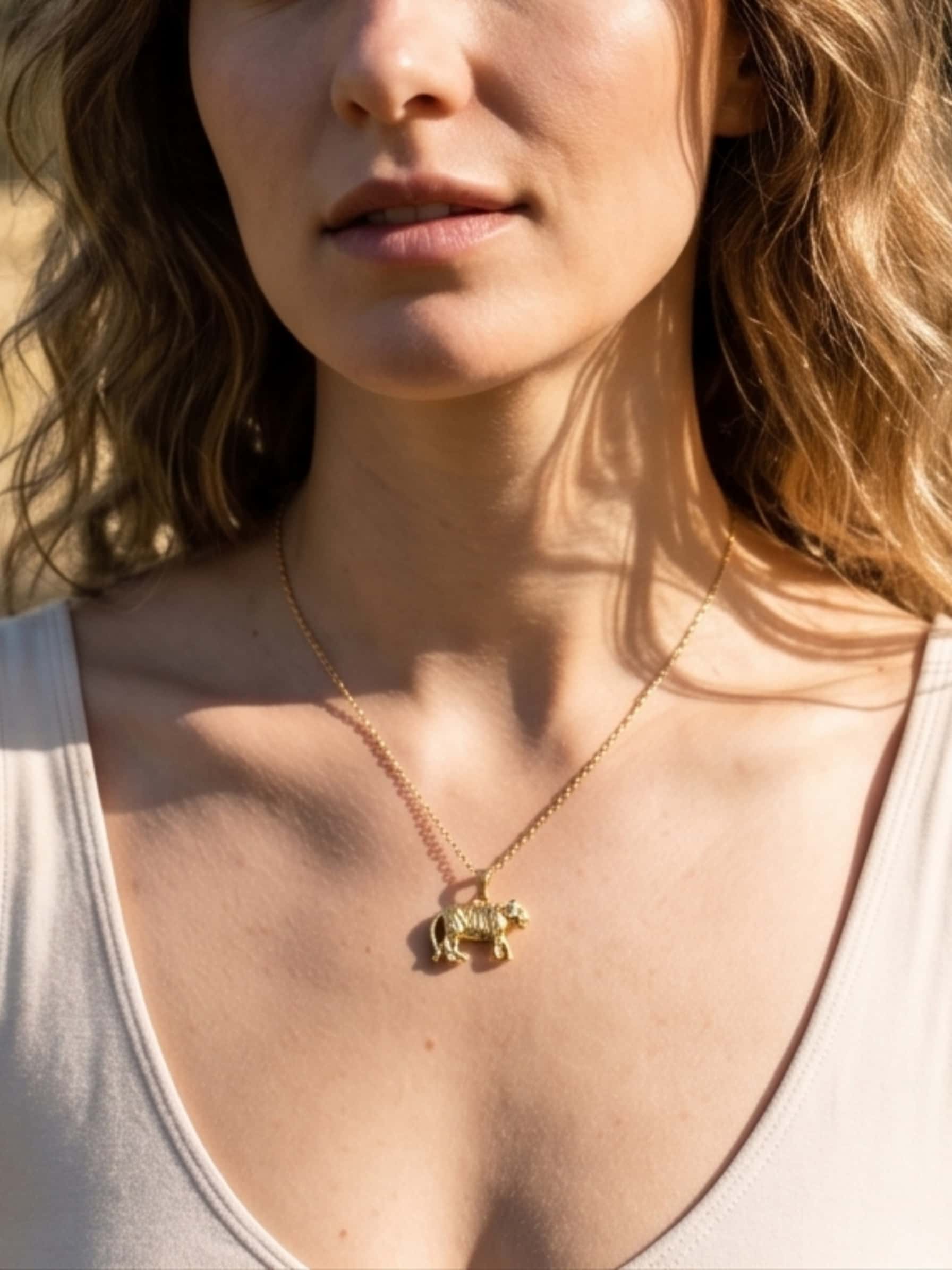 Front view of a model wearing the stainless steel pendant necklace with a tiger charm in a natural outdoor setting