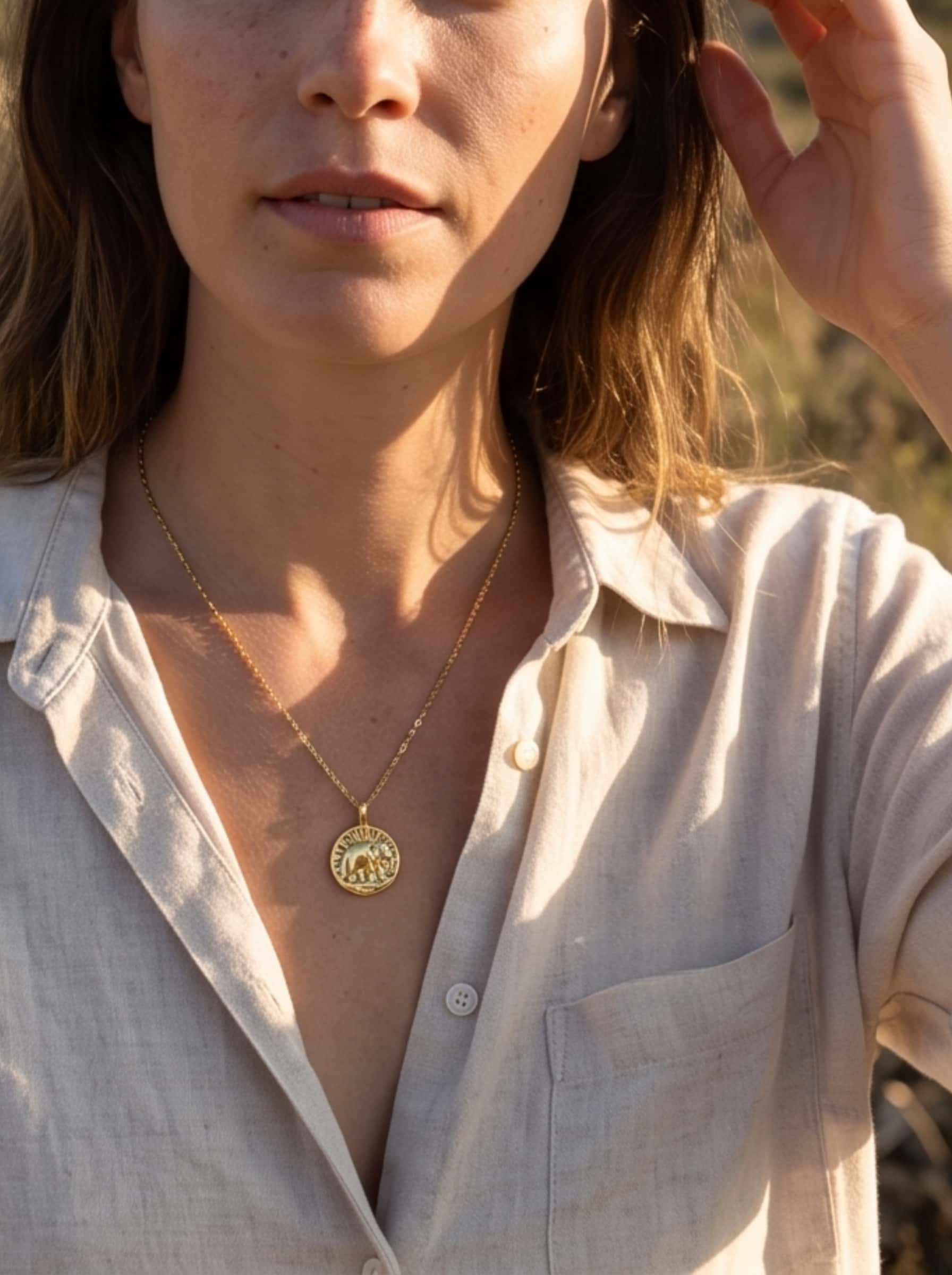 Outdoor lifestyle photo of a model styling the classic elephant necklace gold for an elegant, sun-drenched aesthetic