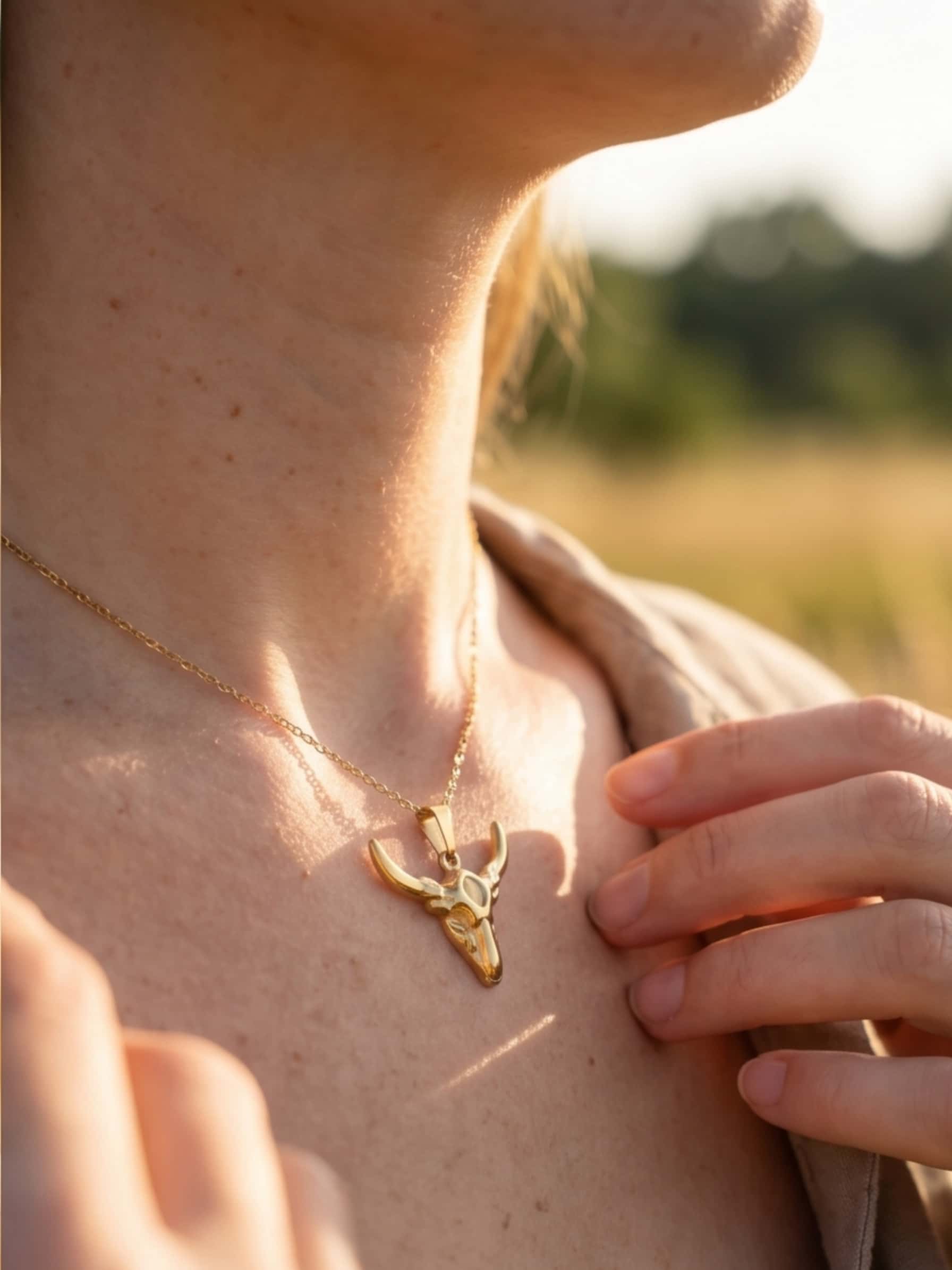 Close up lifestyle shot of a woman adjusting her stainless steel pendant necklace, glowing in the warm golden hour sunlight