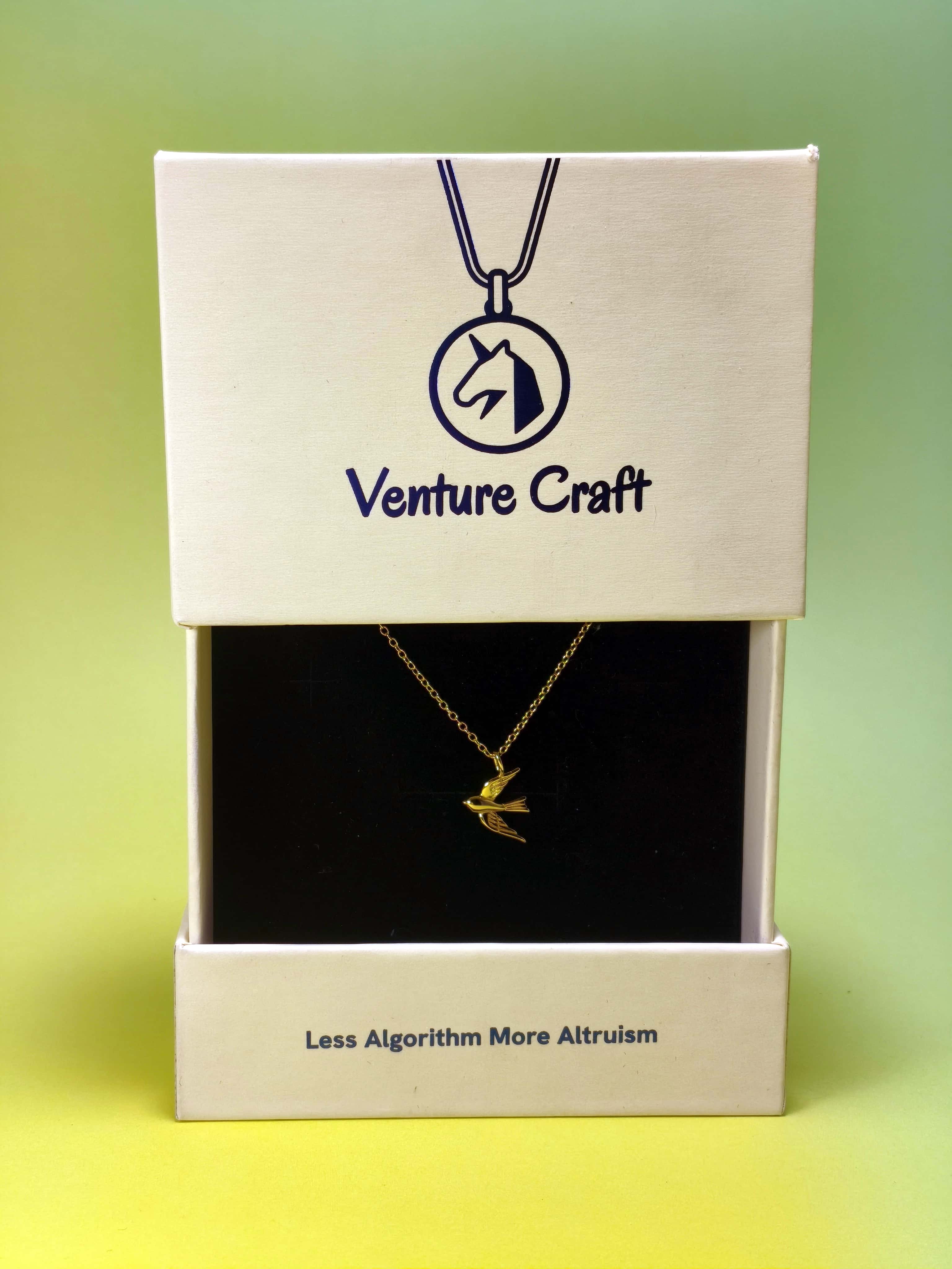 Gold necklace in a 'Venture Craft' gift box with a gradient green background