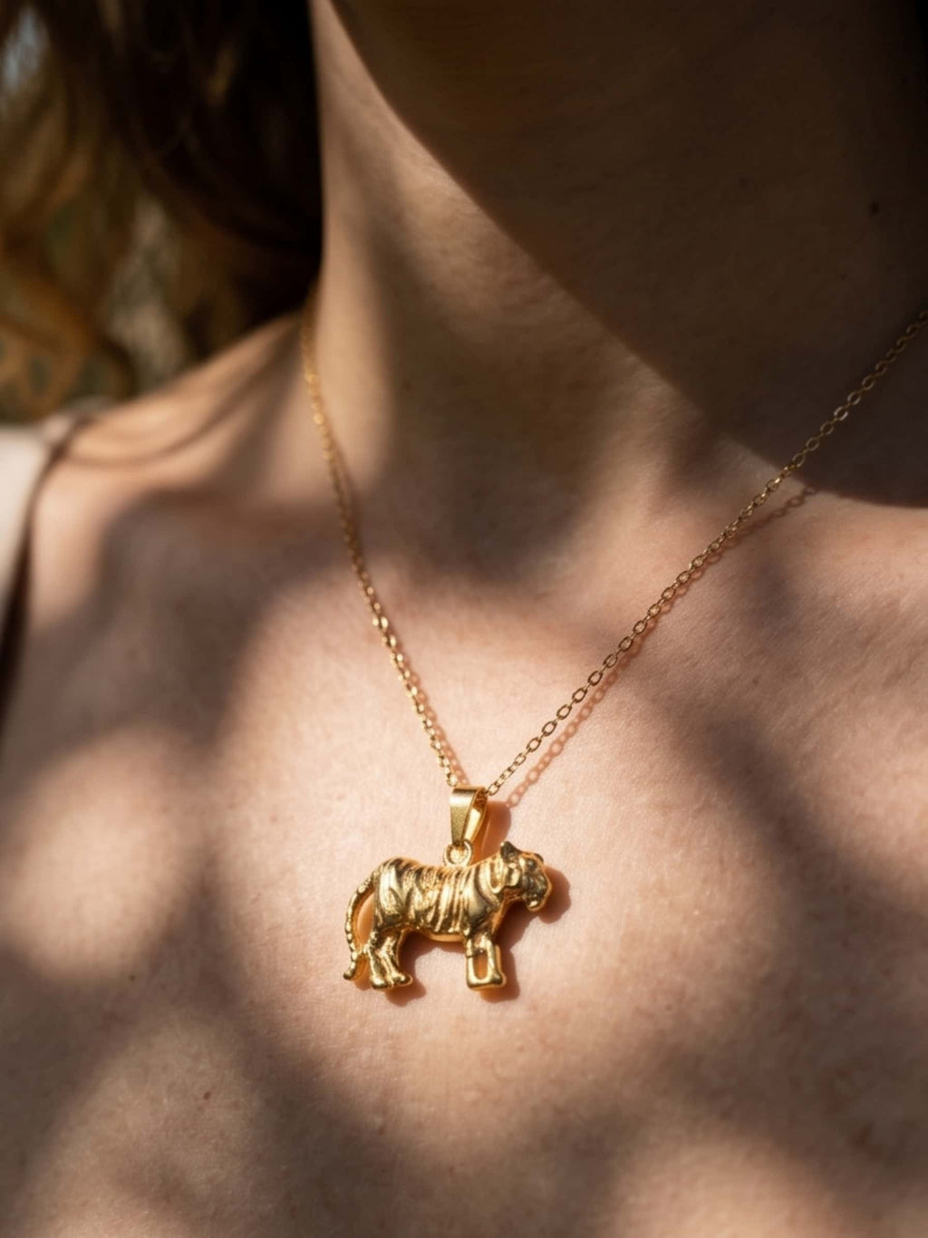 Close-up of a woman wearing the gold tiger necklace, highlighting the detailed animal texture under natural sunlight