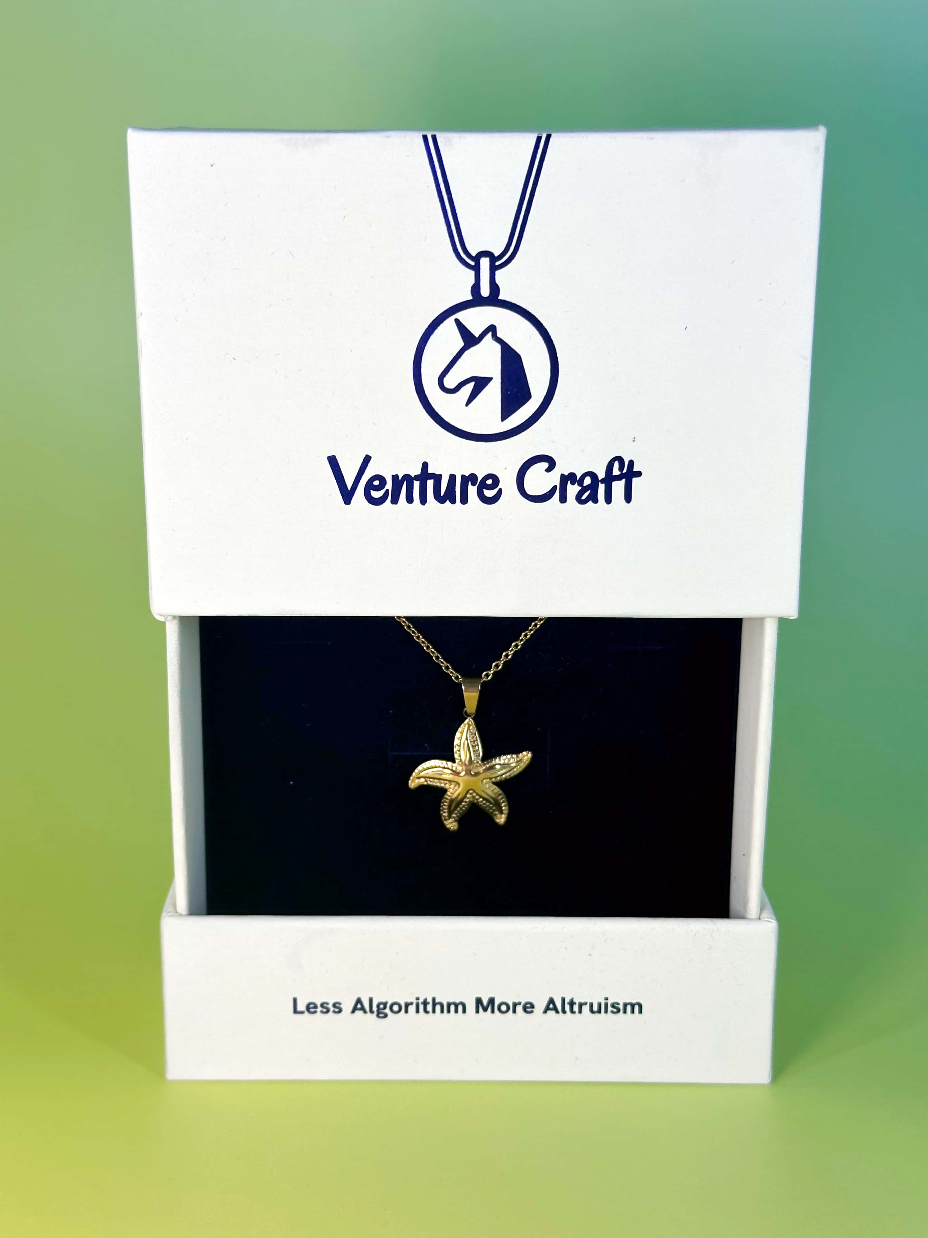 The Venture Craft premium brand gift box holding the gold starfish necklace, featuring the slogan Less Algorithm More Altruism
