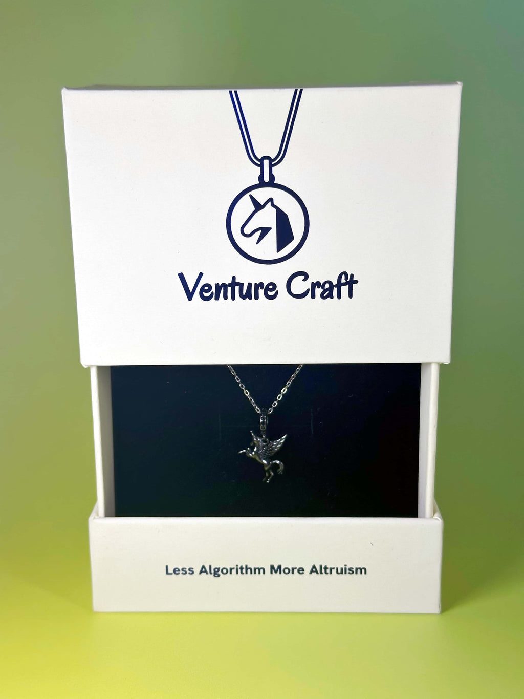 The sterling silver unicorn necklace elegantly displayed inside the official Venture Craft white jewelry gift box, featuring the brand logo and the slogan 'Less Algorithm More Altruism'