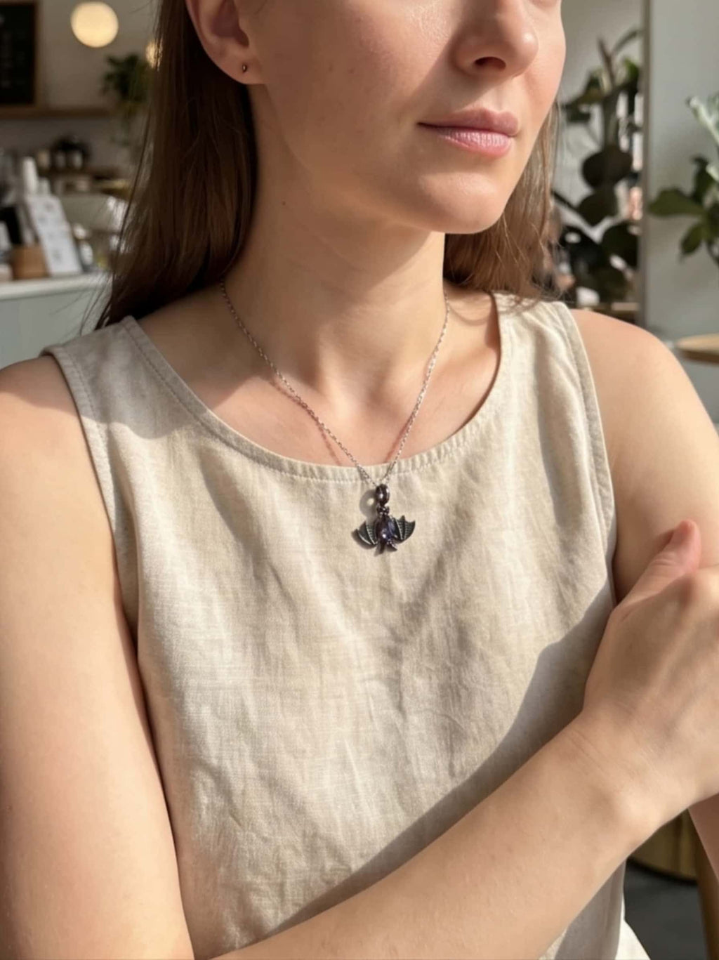 Lifestyle shot of a woman modeling a gothic bat necklace in a bright, modern setting