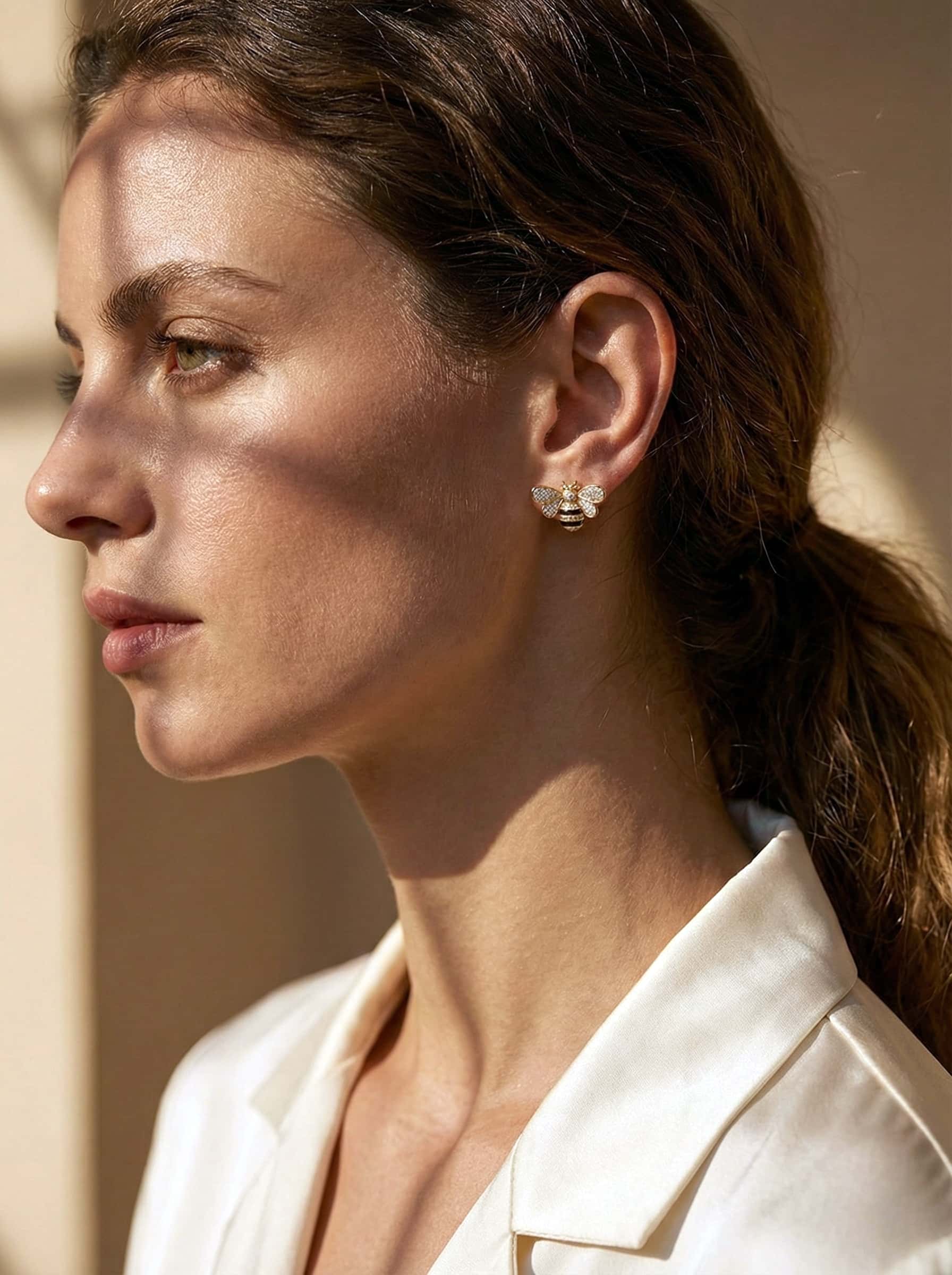 Close-up of a woman wearing bee earrings with a neutral background