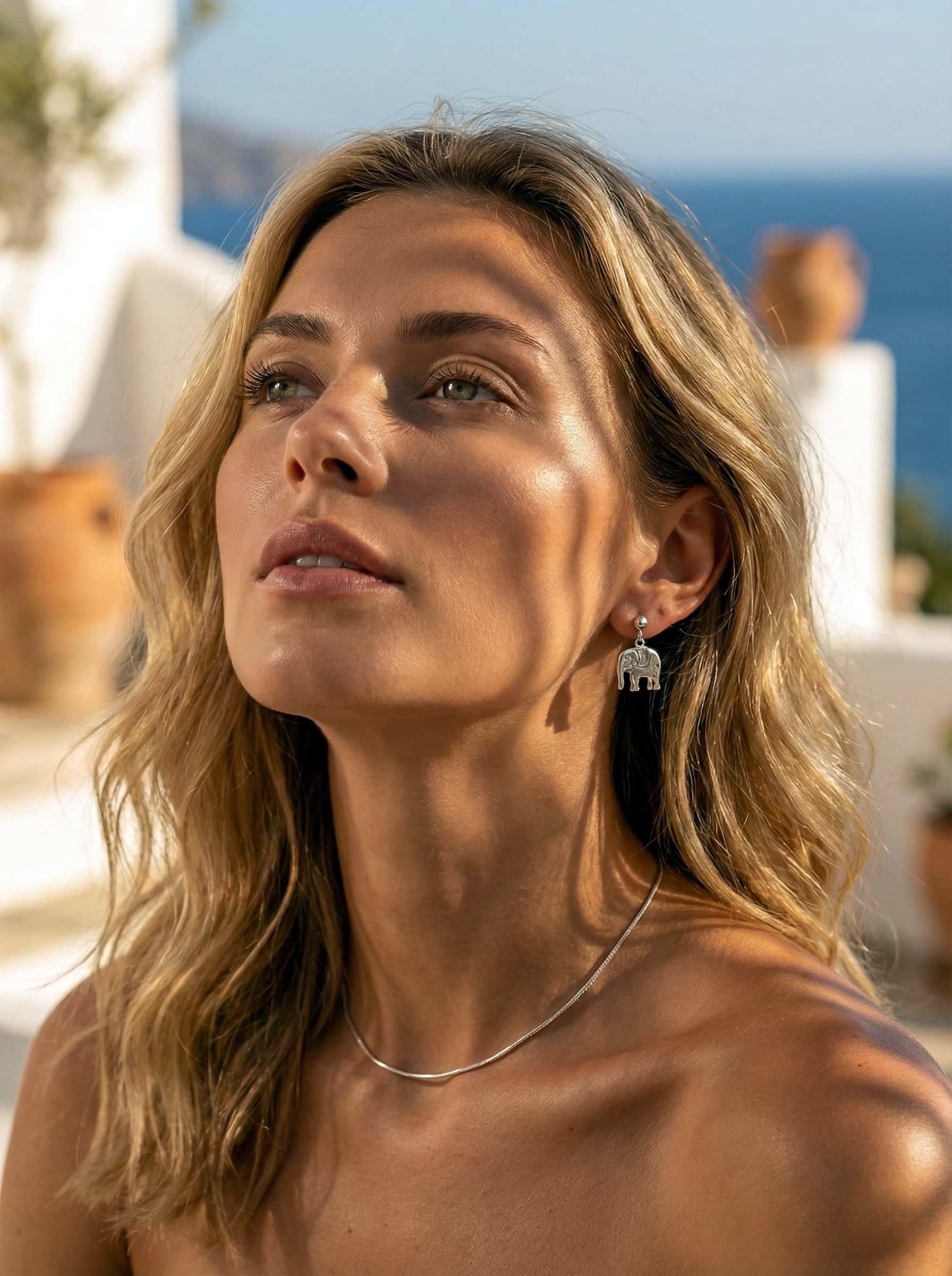 Woman with blonde hair and earrings against a scenic background
