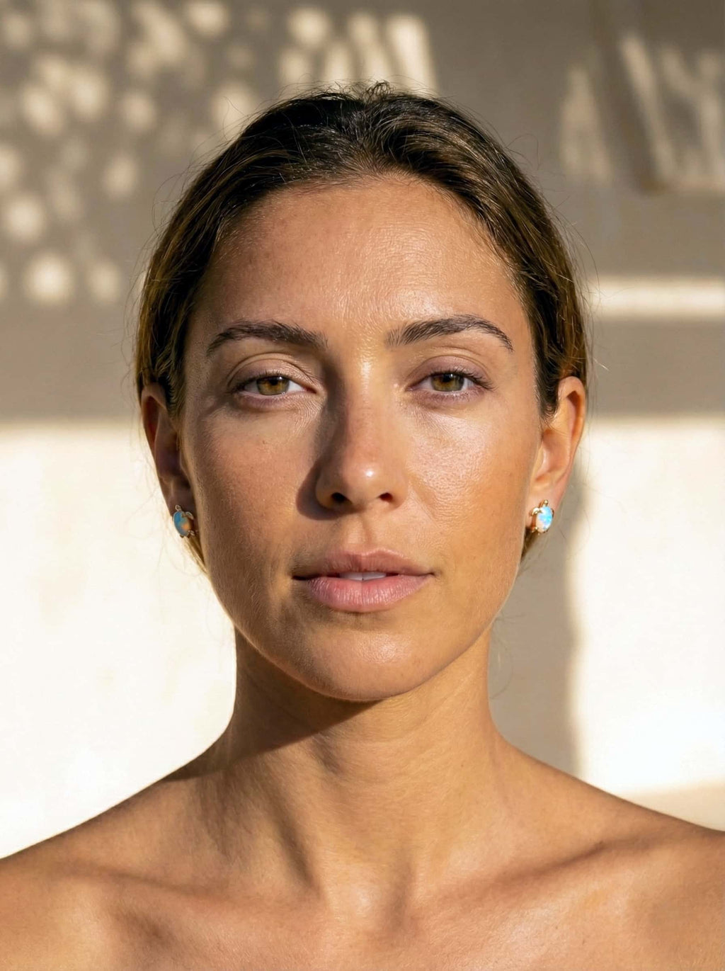 Woman with short hair and turtle earrings against a neutral background