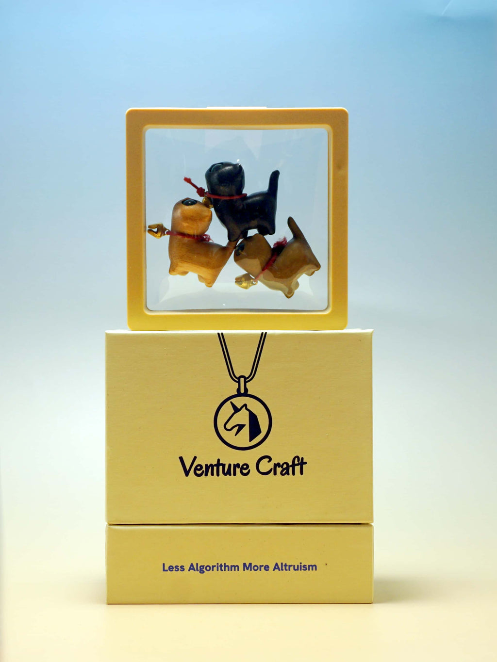 Venture Craft in a clear display wooden cat figurines on a yellow gift box with a gradient background