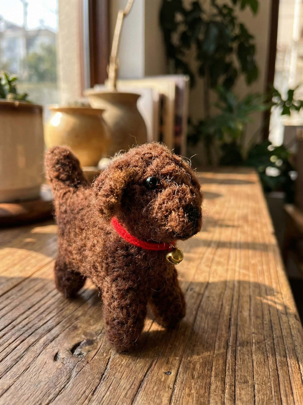 Stuffed brown felt ornament dog with a red collar on a wooden surface