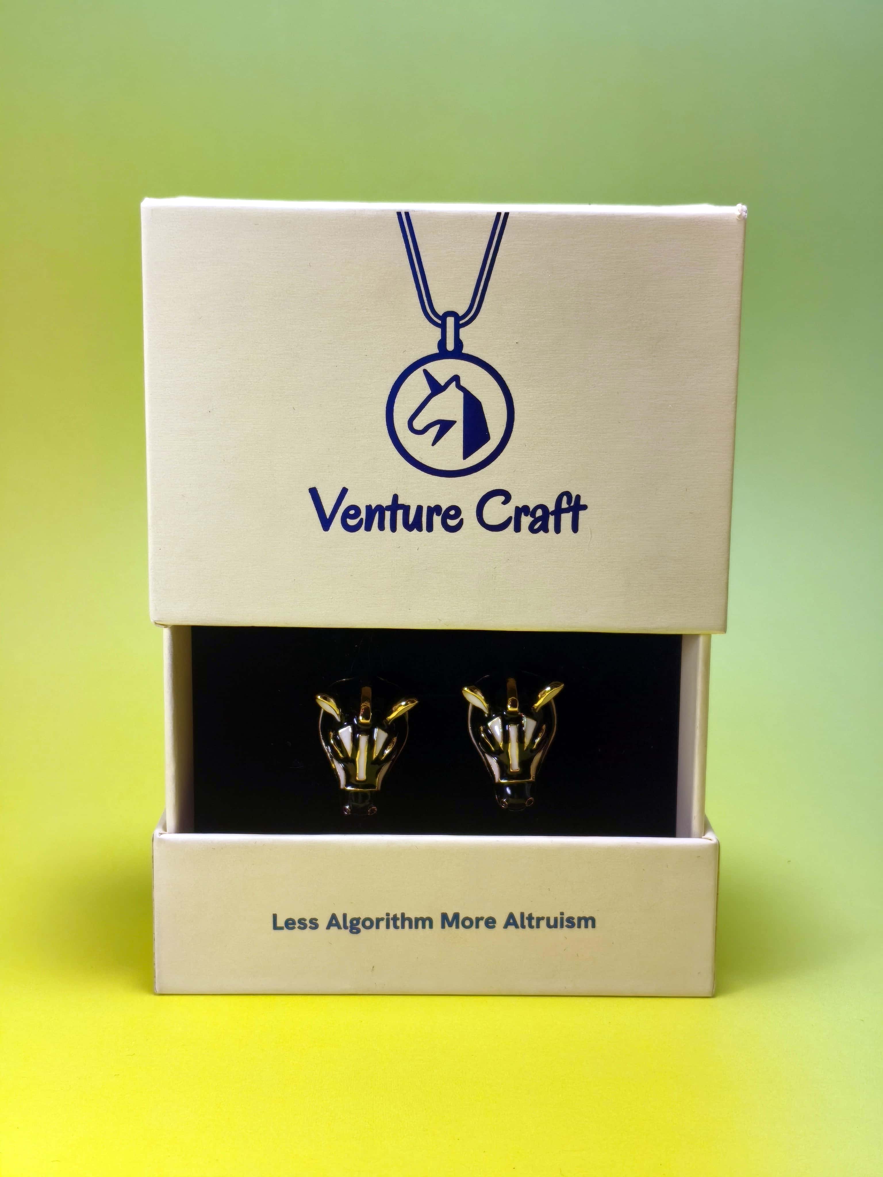 Gold zebra earrings set in a 'Venture Craft' gift box on a gradient background